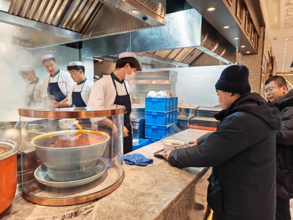 In a Lanzhou beef noodle restaurant,customers are lining up to get their orders.
